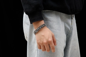 Gros plan d'un bracelet punk rétro en métal avec maillons en croix gothiques sur le poignet