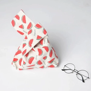 Detail of linen knot bag with fresh watermelon print and glasses for size reference