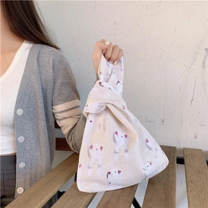 Detail of a minimalist linen wrist bag with rabbit print and Japanese knot handle design