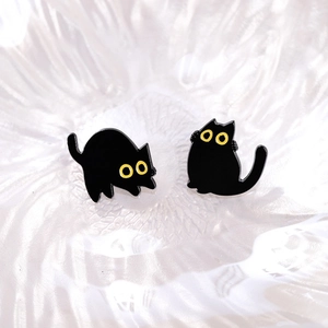 Lindos aretes de gato negro con ojos amarillos en una bandeja de cerámica blanca