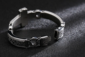 Close-up of gothic stainless steel bracelet with cross pendant and intricate engravings
