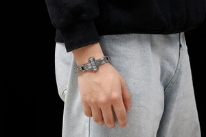 Detail of vintage silver punk cross bracelet with embossed square links on male wrist