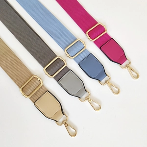 Detail of colorful adjustable canvas bag straps with gold metal hooks and leather joints