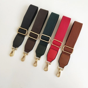 Detail view of colorful canvas bag straps with gold metal hooks and adjustable buckles