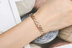 Close-up of a rose gold twisted cable cuff bracelet worn on a wrist for a stylish look