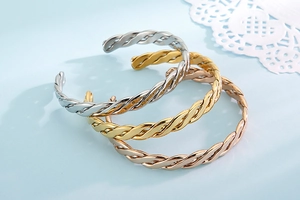 Detailed view of twisted cable metal bangles in gold, silver, and rose gold finishes