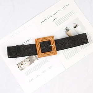 Detail of black woven belt featuring a square wooden buckle on a minimalist magazine background