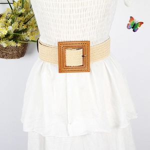 Detail view of woven straw belt with square wood-style buckle on a white dress