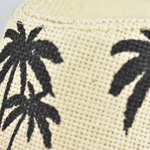 Macro detail of breathable straw fabric with tropical palm tree print on summer sun hat