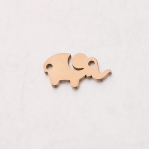 Close-up of rose gold elephant pendant with polished finish on marble surface