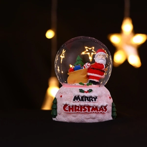 Gros plan d'une boule à neige de Noël lumineuse avec le Père Noël et une base rose festive