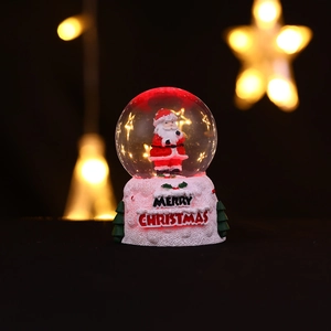 Gros plan d'une boule de cristal de Noël lumineuse avec Père Noël et lumières LED