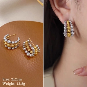 Macro detail and on-ear look of three-row beaded titanium steel hoop earrings in mixed tones