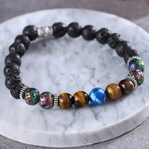 Lava rock and tiger eye stone bead bracelet with a blue earth charm on white marble base
