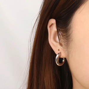 Close-up of model wearing a minimalist polished silver C-shaped chunky hoop earring