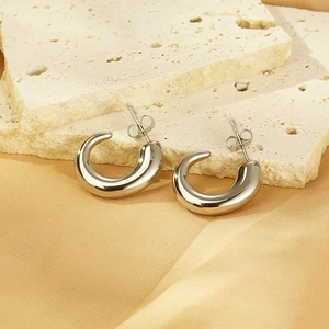 Polished silver stainless steel C-shape earrings on stone and silk fabric