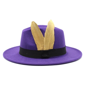 Detail of purple wool fedora hat featuring golden feather ornaments and a black ribbon