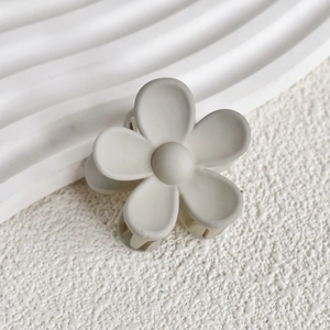 Close-up of a matte beige flower hair claw clip with a minimalist five-petal design