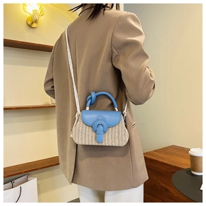 Detail of blue leather flap and woven strap on a stylish straw crossbody handbag