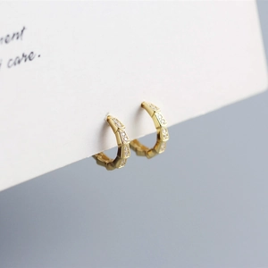 Close-up of gold S925 silver hoop earrings featuring a textured snake scale pattern and cubic zirconia