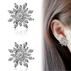 Detail of silver snowflake stud earrings with crystals and model wearing display