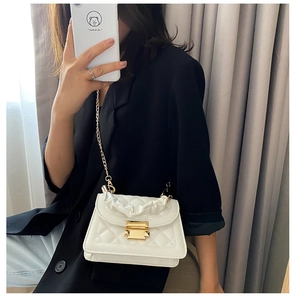 Close-up of white quilted crossbody bag with chain strap and scrunchie handle details