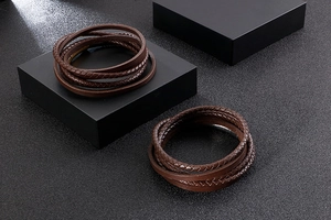 Detailed view of layered brown braided leather bracelets on black display stands