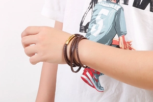 Detail of brown braided leather wrap bracelet with a secure gold magnetic metal clasp