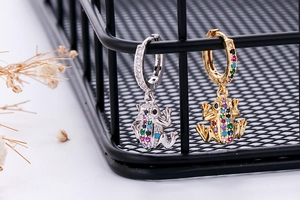 Detail of frog pendant hoop earrings with colorful cubic zirconia on wire mesh