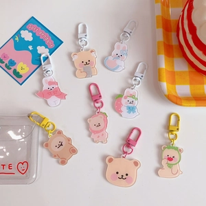 Detailed view of eight colorful acrylic cartoon bear and rabbit keychains on a white surface