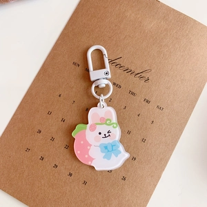 Close-up of acrylic white rabbit keychain with strawberry charm on a paper calendar
