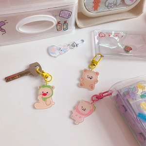 Flat lay of cute acrylic bear and rabbit charms with metal keyrings on a white desk