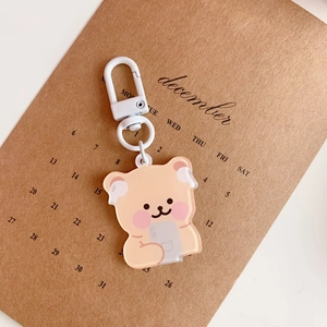 Close-up of a cute acrylic bear keychain with a phone on a vintage calendar background