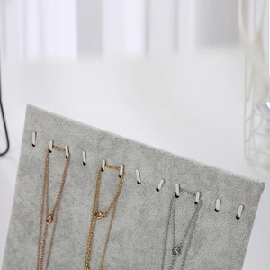 Detail view of grey velvet L-shape jewelry stand with multiple rows of necklace hooks