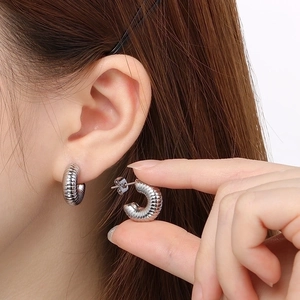 Close-up of silver stainless steel C-hoop earrings with detailed ribbed texture and finish