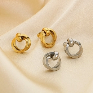 Detail of twisted knot stud earrings in gold and silver finish on silk fabric
