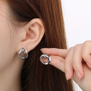 Close-up of geometric silver hoop earrings featuring a polished metal ball accent