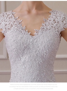 Detailed view of bridal gown with floral lace embroidery and white pearl beads on V-neck