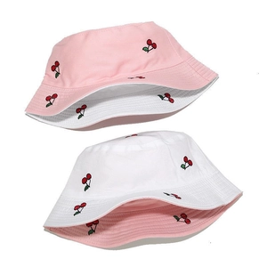 Macro detail of reversible bucket hat with red cherry embroidery on pink and white fabric