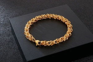 Close-up of golden braided link chain bracelet with lobster clasp on premium black box