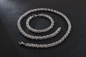 Polished silver stainless steel braided chain necklace and bracelet set on black texture