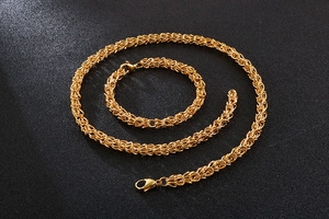 Close-up of gold Byzantine crown necklace and bracelet set on black background