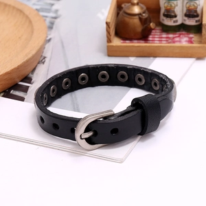 Detail of punk leather bracelet showing metal buckle and texture on a natural wooden tray