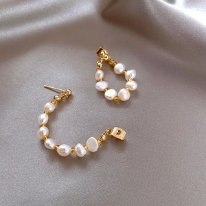 Elegant pearl drop earrings with gold beads on luxurious silver satin background