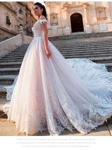Detailed lace embroidery on a white off-the-shoulder wedding dress with long train