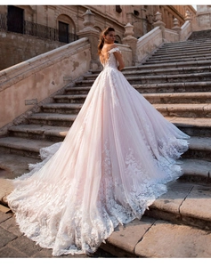 Detailed back view of long lace train wedding dress on classical stone steps outdoors