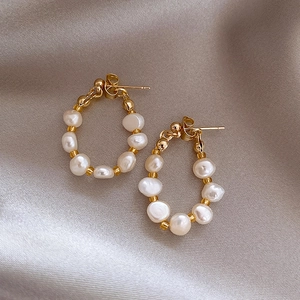 Elegant gold earrings with baroque pearls on soft silk fabric, minimalist retro design
