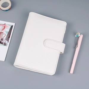 Flat lay of white faux leather ring binder notebook with secure buckle strap and pink pen