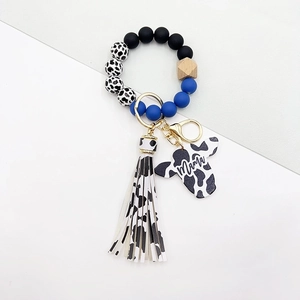 Detail of western wristlet keychain with blue beads, cow print tassel, and Mama pendant