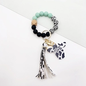 Macro detail of cow print tassel and Mama cow head tag on a western style keychain